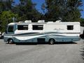 A 2000 Ford Motorhome in blue and white with aerodynamic graphics and multiple roof vents parked in a lot