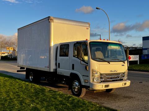 A 2017 Isuzu NPR box truck with a white cargo box and black tires parked on a street