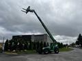 A green 2014 JLG 10054 telehandler with an extending boom and fork attachment positioned on a paved area