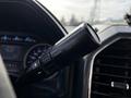 A close-up of a black turn signal lever inside a 2018 Ford F-550 with labeled buttons for turning left and right