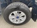 A silver alloy wheel with a Ford logo and an all-terrain tire labeled Encounter mounted on a 2019 Ford F-150