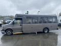 A 2017 Chevrolet Express bus with a dark gray exterior and large windows parked on a wet surface