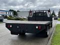 A black 2017 Ford F-550 flatbed truck is parked with its rear facing the viewer showcasing the bed and taillights