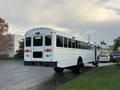 A white 2015 International 3000 school bus parked with a prominent rear view showing large windows and black wheels