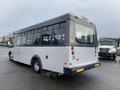 A 2018 Chevrolet Express bus with a white body and gray accents viewed from the rear showing large windows and a smooth, contoured design