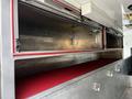 Interior storage compartment of a 1994 Freightliner FL80 featuring metal shelving and a red rubber floor mat