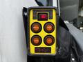 A yellow control panel with buttons labeled for power, deploy, stow, down, and up, attached to a black carrying case