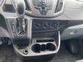 Interior view of a 2018 Ford Transit focusing on the gear shift console with P R N D M options and climate controls with multiple knobs and a cup holder section