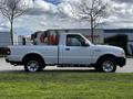 A white 2010 Ford Ranger pickup truck is parked with the driver's side facing the viewer showcasing its two-door cab and chrome wheels