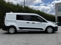 A white 2016 Ford Transit Connect van parked with its side visible featuring a black stripe along the lower body and silver wheels