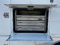 A 2004 Freightliner M2 truck with an open storage compartment revealing three metallic drawers inside