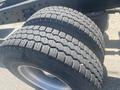 Close-up of two large, treaded tires mounted on a truck axle with visible rubber patterns and a steel rim