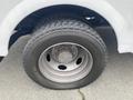 Close-up of a wheel and tire from a 2003 Ford F-450 SD showing a steel rim and rugged tread pattern