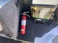 A red fire extinguisher is positioned on a black rubber mat next to a container of fluid inside a 2012 Ford Econoline