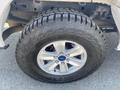 A close-up of a 2017 Ford F-150 tire with a rugged tread pattern mounted on a silver alloy wheel featuring the Ford logo