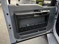 The interior door panel of a 2016 Ford F-550 featuring a gray plastic handle and a storage compartment with grooves for easy grip