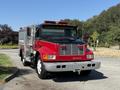 A red and black 1991 International 4600 fire truck with a shiny front grille and emergency lights on top is parked with a side-mounted water tank and equipment compartments
