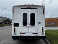 A 2016 Ford Econoline with a white rear, double doors, and a sign indicating wheelchair lift installation