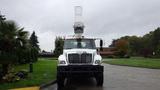 A 2005 International 7400 truck with a bucket lift attachment raised above the cab