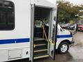 A 2015 Chevrolet Express with its front doors open revealing stairs leading up to the driver's cabin and a yellow handrail