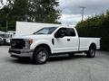 A white 2017 Ford F-250 truck is parked with its side facing the camera showcasing its cab body style and chrome front grille