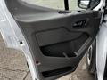 The interior door panel of a 2021 Ford Transit featuring a textured black design with a handle and storage compartment