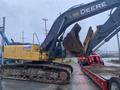 A yellow 2014 John Deere 350G excavator with a large bucket and tracks positioned on a trailer ready for transport