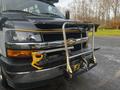 A 2018 Chevrolet Express van with a yellow and black front bumper guard and an integrated towing hitch attached to the front