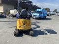 A yellow 2022 John Deere mini excavator with tracks and a raised operator's seat is parked in the foreground