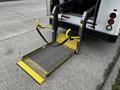 A yellow and black accessible ramp is extended from the back of a 2016 Ford Econoline van