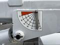A gauge displaying a range of angles from -15 to 75 degrees on a white equipment arm with a metallic indicator needle