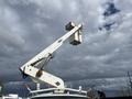 A 2008 Ford Econoline van with an elevated white bucket truck attachment for utility work