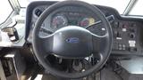 Steering wheel and dashboard of a 2011 Ford Econoline featuring gauges and control buttons visible