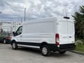 A white 2022 Ford Transit van is parked with its rear view visible showcasing its large cargo space and distinctively designed tail lights
