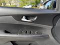 Door panel of a 2024 Kia Forte5 featuring a set of control buttons for windows and mirrors along with a chrome door handle