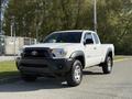 A white 2015 Toyota Tacoma pickup truck with a black front grille and off-road tires parked on a paved surface