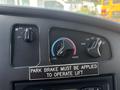 Dashboard controls of a 2008 Ford E-350 featuring knobs for fan speed temperature and airflow along with a warning label about the park brake for lift operation