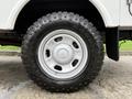A close-up of a white wheel and tire from a 2015 Ford F-350 SD featuring a rugged tire tread pattern and a simple steel rim design