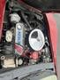 Engine of a 1970 Chevrolet Corvette featuring a shiny chrome air filter and red ignition wires along with various mechanical components