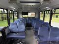 Interior of a 2020 Chevrolet Express bus featuring rows of blue fabric seats with seatbelts and a spacious layout