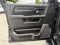 Black interior door panel of a 2024 RAM 2500 featuring buttons for windows and locks, a door handle, and textured armrest