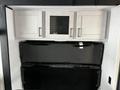 A modern kitchen area featuring silver cabinetry with three upper cabinets and a lower black foldable table or counter surface