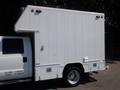 A 2012 Ford F-550 with a large white cargo box attached to its bed featuring side doors and a simple design