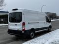 A 2021 Ford Transit van in white with a sliding door and high roof viewed from the rear on a snow-covered street