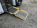 A yellow wheelchair ramp extended from the side of a 2017 Chevrolet Express vehicle