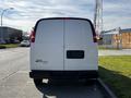 A rear view of a 2015 Chevrolet Express van with a plain white exterior and no visible license plate