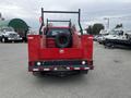 A red 2011 Ford F-250 SD truck with a flatbed and a spare tire mounted in the bed visible from the rear