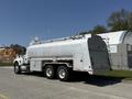 A silver 2009 International 7500 tanker truck with a rounded tank and side compartments parked on a paved surface