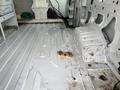 A 2008 Ford Econoline interior showing the van's metal flooring with some scattered debris and a small brown stain