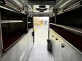 Interior view of a 1994 Freightliner FL80 showing shelves along the sides and a metallic floor with hooks and a storage container near the entrance